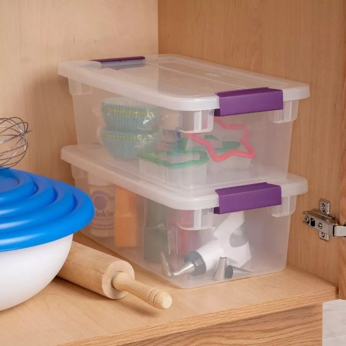 Plastic storage bins with purple handles neatly organizing baking tools and supplies on a kitchen shelf, offering a tidy and convenient solution for your culinary needs.