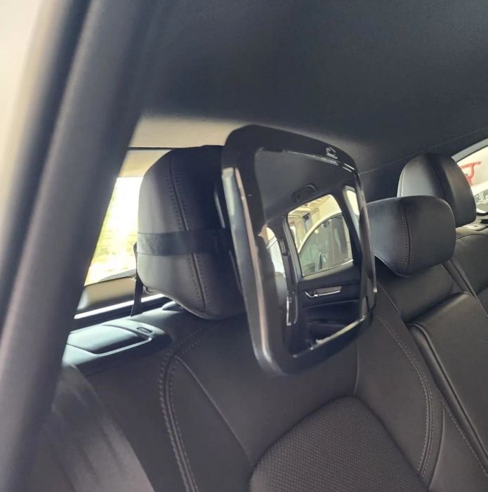 A transparent plastic barrier attached to a car seat headrest, designed to provide extra safety during travel.