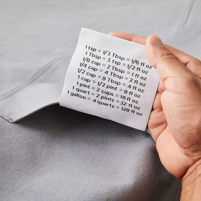 The oversized conversion chart tag tucked into the pocket of a grey apron