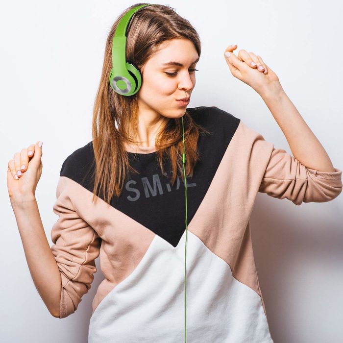 A model wearing lime green over-ear headphones with a cord