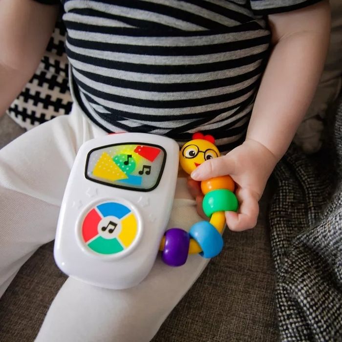 A baby holding a colorful, musical toy with various shapes, suggesting a focus on educational toys for children during shopping.