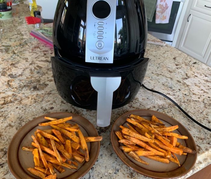 Reviewer’s photo of the air fryer alongside plates of homemade French fries