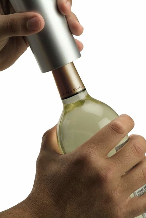 the wine opener securely gripping the top of a wine bottle