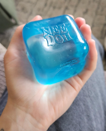 reviewer holding the blue version of the stress ball in their hand