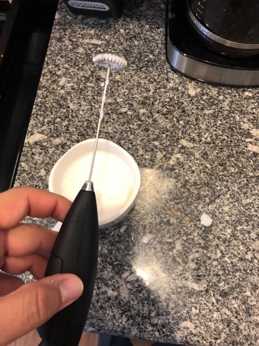 A reviewer showcasing a compact frothing wand