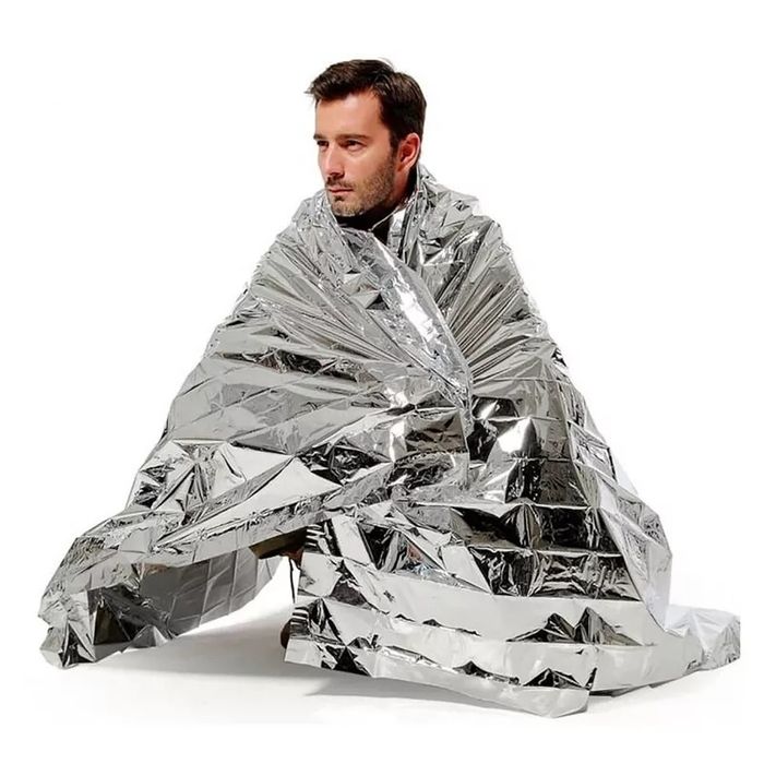 A person wrapped in a shiny, reflective emergency blanket, typically used in outdoor survival situations.