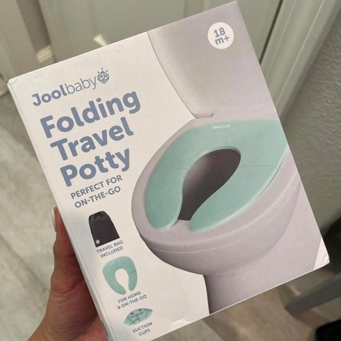 A person holds a Jool Folding Travel Potty box, emphasizing its convenience for home and travel use, complete with suction cups and a travel bag.