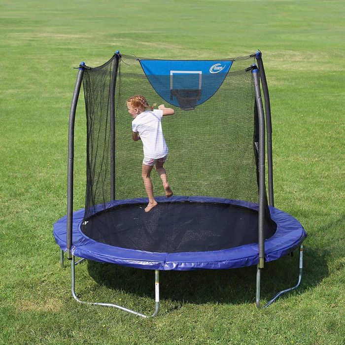A blue and black trampoline placed on grass, with a child having fun inside.