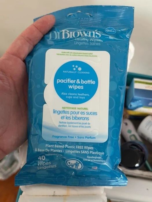 A hand holds a package of Dr. Brown’s pacifier and bottle wipes, highlighting their natural cleaning formula and plastic-free materials.