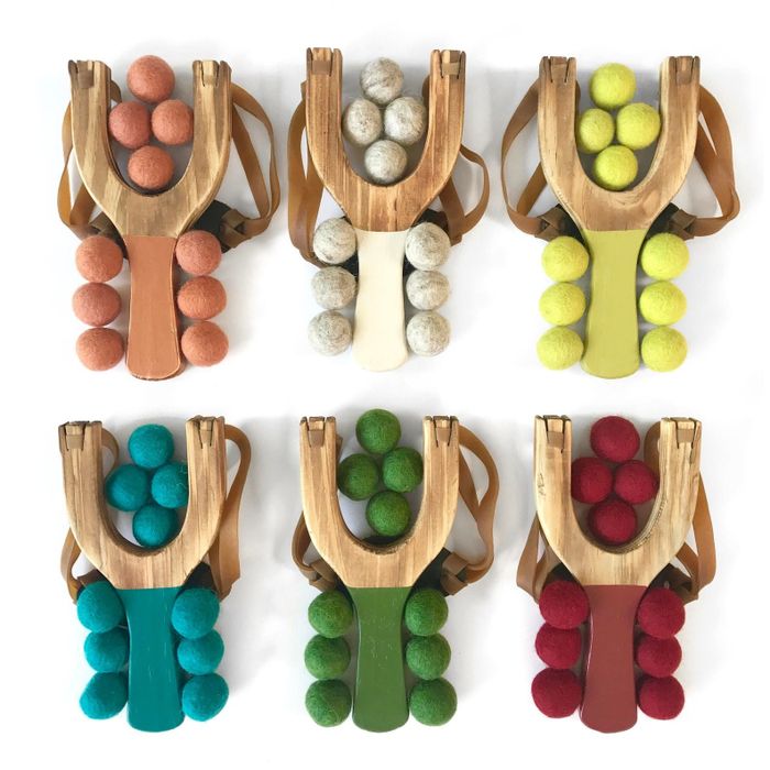 A set of six slingshots with multi-colored handles and soft pom balls, ready for fun and play.