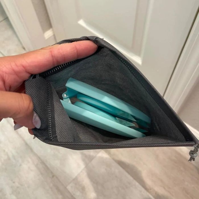 A gray pouch lies open on a tiled floor, revealing light blue notebooks inside.