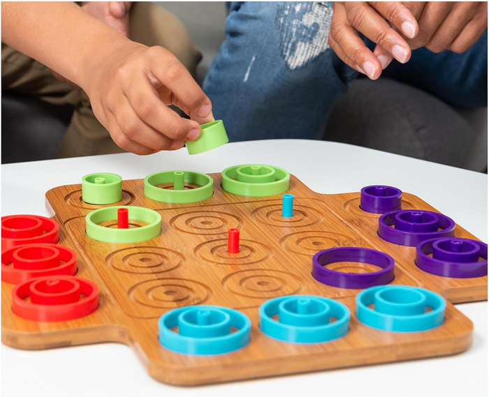 kids' hands engaged in a board game, placing vibrant rings on a wooden playing surface
