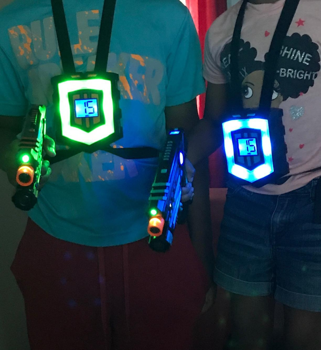 A reviewer's photo showing two children wearing the vests and holding the laser guns.