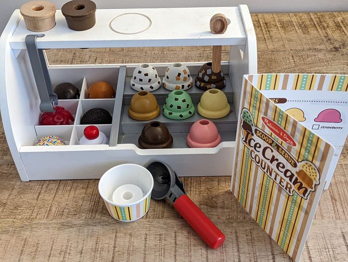 An imaginative playset featuring a toy ice cream counter, complete with assorted pretend flavors and fun accessories