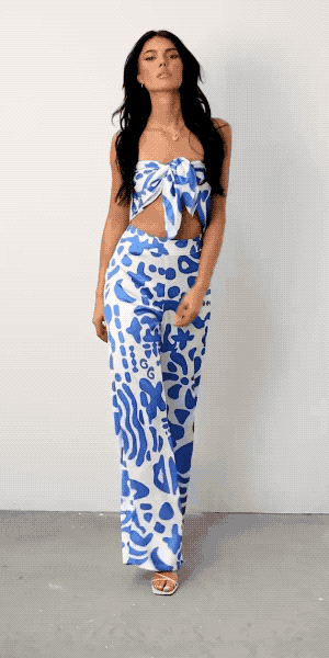 A model showcasing a stylish blue patterned two-piece ensemble featuring a tied crop top and matching pants