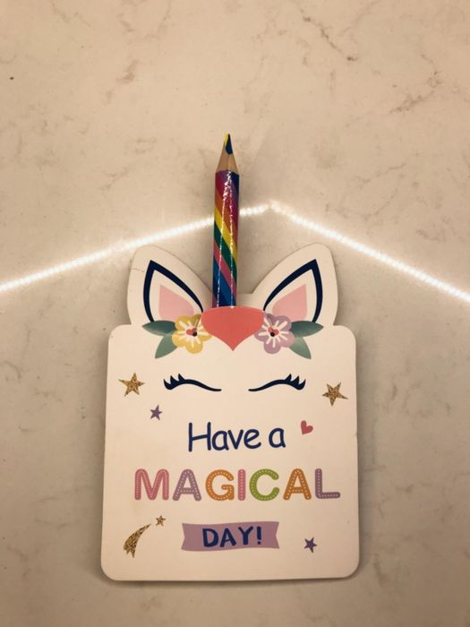 A reviewer’s photo of a unicorn-themed card that says 'Have a magical day' with a rainbow pencil sticking out of it.