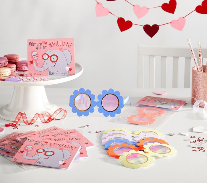 Valentine's cards featuring playful glasses on a table, surrounded by small gifts, macarons, and heart garlands—perfect for festive shopping ideas