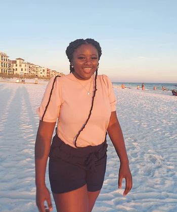 A reviewer is sporting the black version of the shorts on a beach.