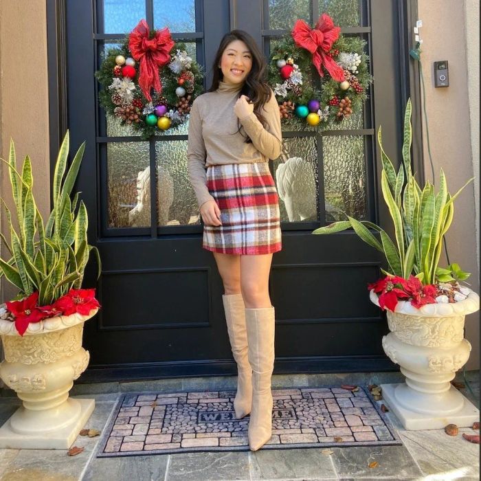 Reviewer wearing a red and white skirt paired with a beige top and boots