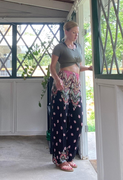 another reviewer photographed in the printed pants, posing by a front door