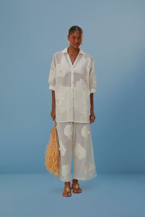 A model showcasing sheer pants adorned with white floral patterns.