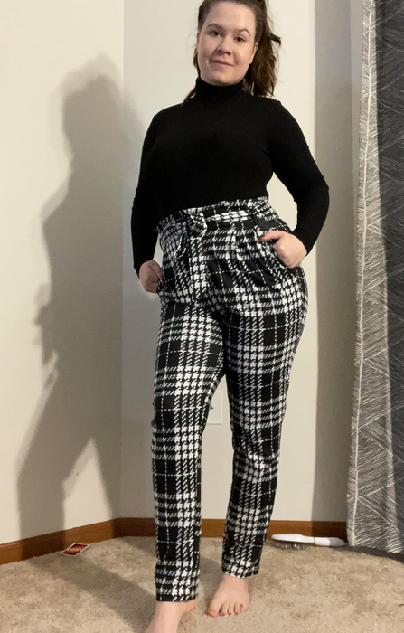 Another reviewer models the black and white plaid trousers, complemented by a sleek black long-sleeve top.