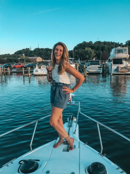 A reviewer is wearing blue paperbag shorts while enjoying a boat ride.
