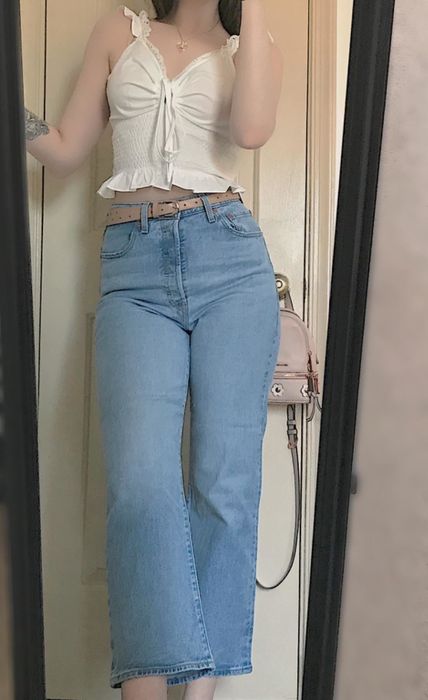 A reviewer wearing light blue jeans with a belt for a stylish look.