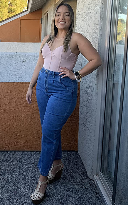 A reviewer is rocking dark wash jeans with a pink corset top.