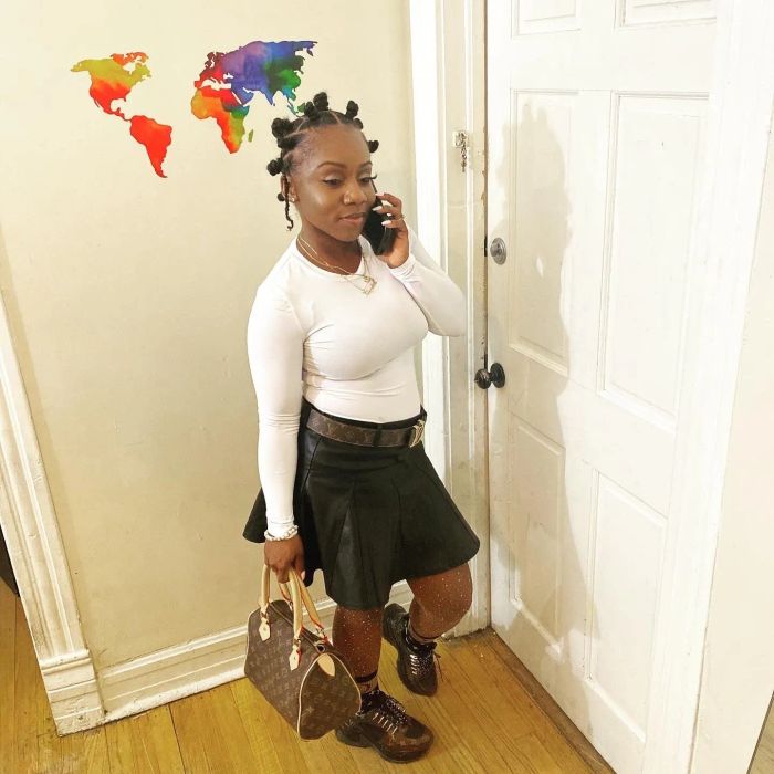 The black skirt is paired with a white long-sleeve top.