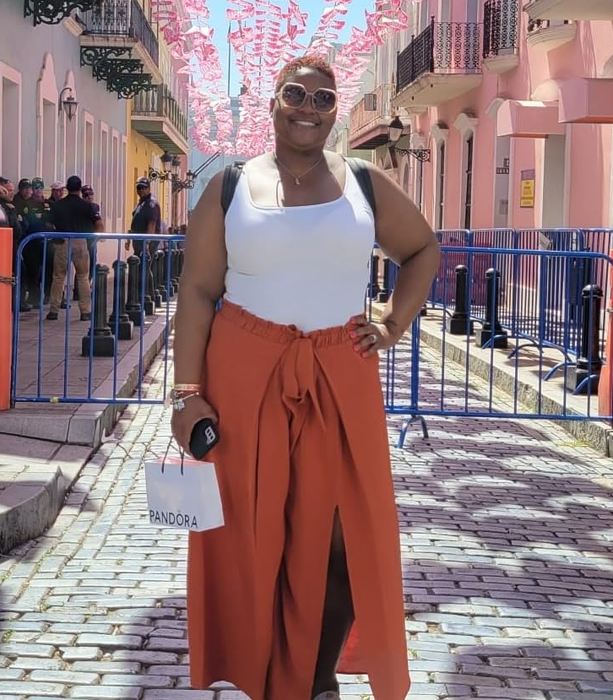 A reviewer styled in rust-colored side-slit pants paired with a simple white tank top