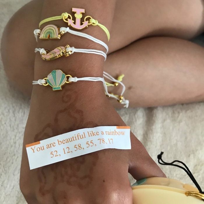 A reviewer displaying four charm bracelets on their hand while showing off a paper fortune.