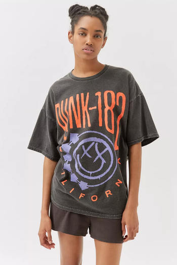 A model wearing an oversized dark gray Blink-182 tee.