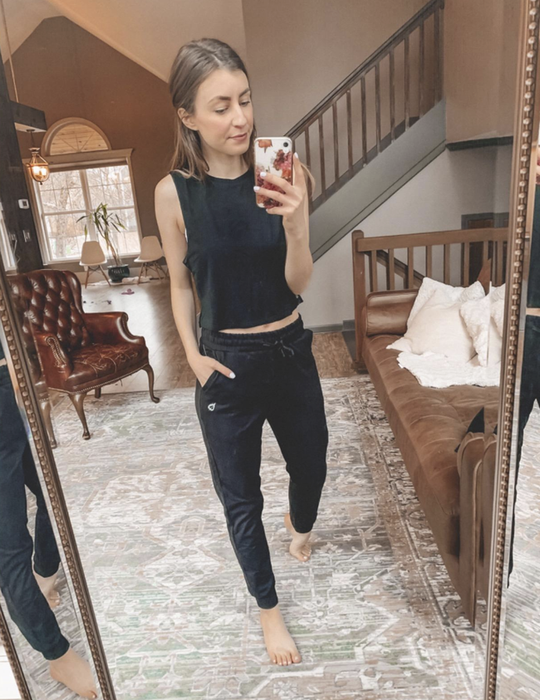 A reviewer wearing black joggers with an elastic waist and side pockets.