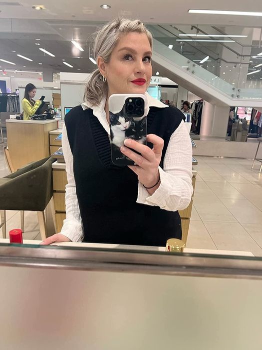 reviewer styling a black sweater vest with a white button-down shirt underneath