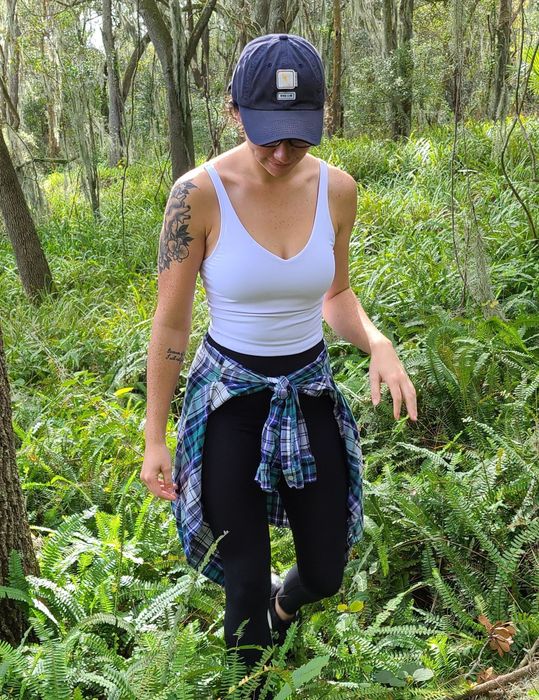 Reviewer seen hiking in a white crop top paired with leggings and a flannel tied around the waist