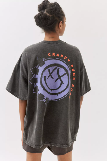 A model showing the back of an oversized dark gray T-shirt featuring the purple Blink-182 logo.