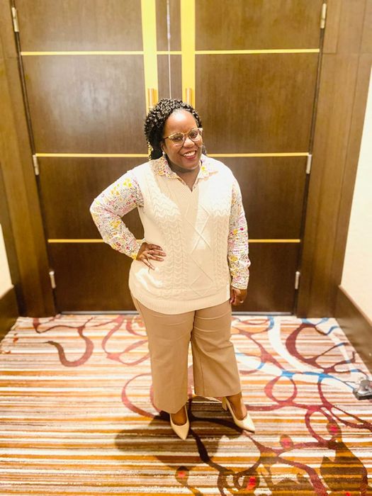 reviewer donning a white sweater vest over a floral blouse
