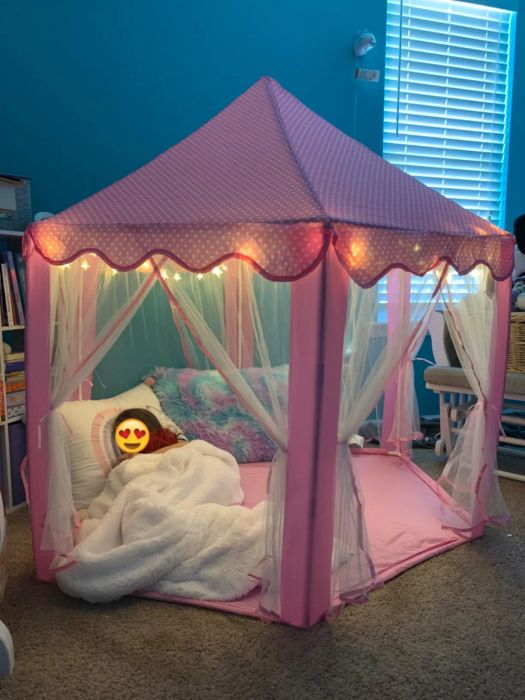 A heartwarming photo of the reviewer's child all snug inside the soft, pink-lit tent.