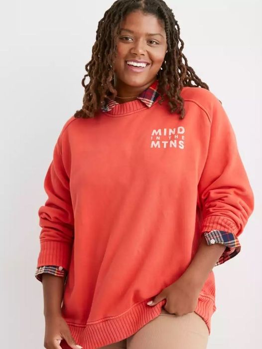 A model wearing the orange pullover sweater