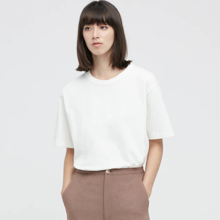 A model wearing the white t-shirt, casually posing with hands in pockets.