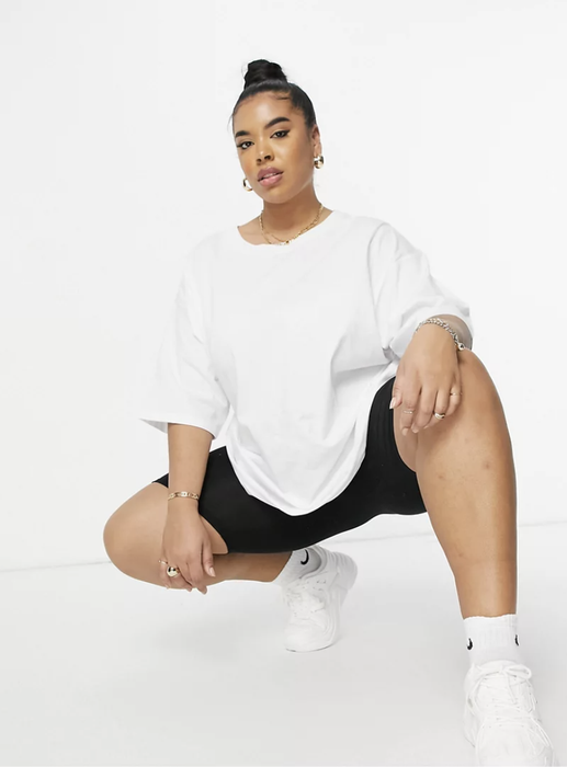 model styling an oversized white tee paired with black bike shorts