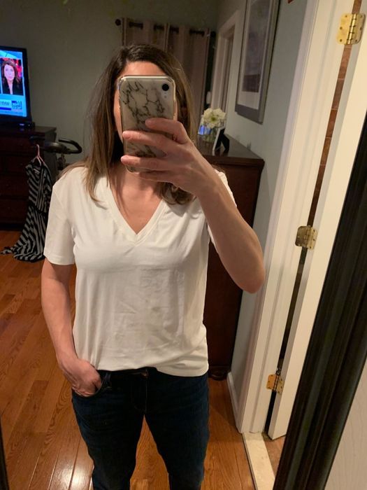 A mirror selfie of a reviewer wearing the white V-neck tee with jeans.