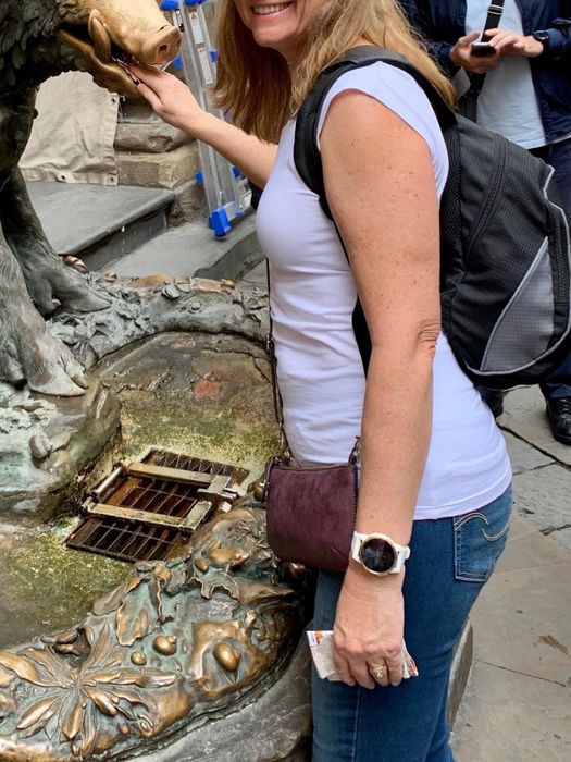 reviewer’s side photo wearing the long tee while feeding a pig statue