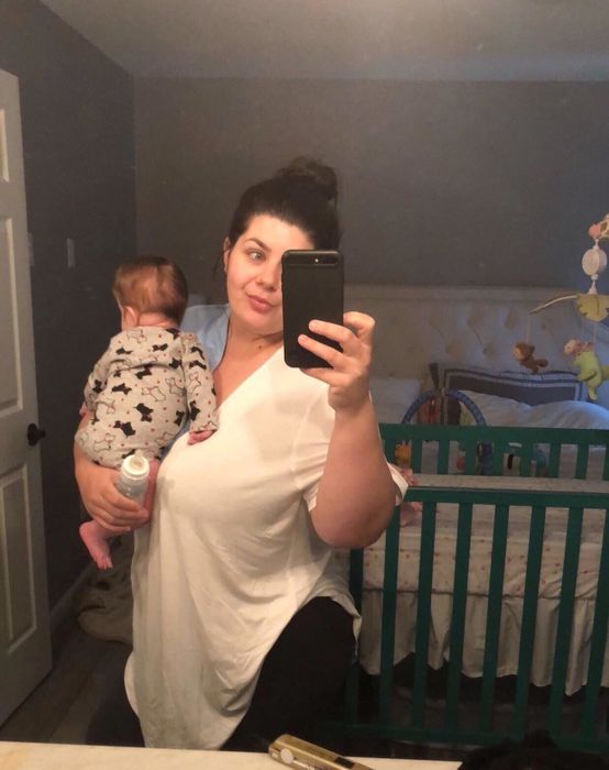 mirror selfie of the reviewer in a t-shirt while holding a baby