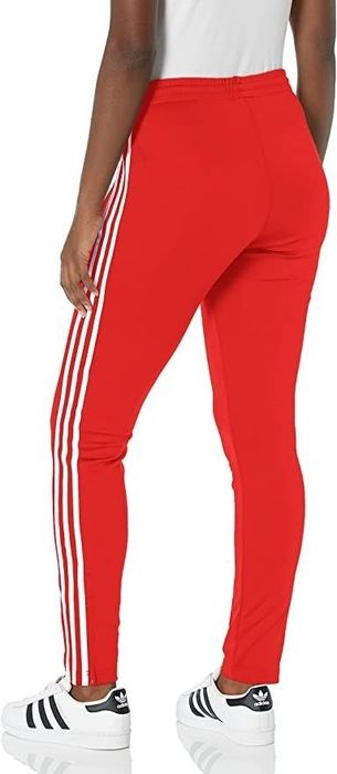 A model showcasing the red pants featuring three white stripes.