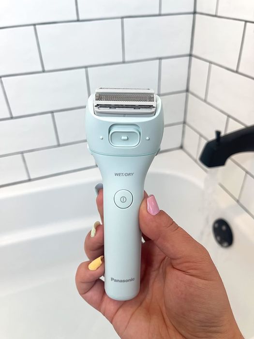 A reviewer’s photo shows them holding the Panasonic electric shaver over a bathtub.