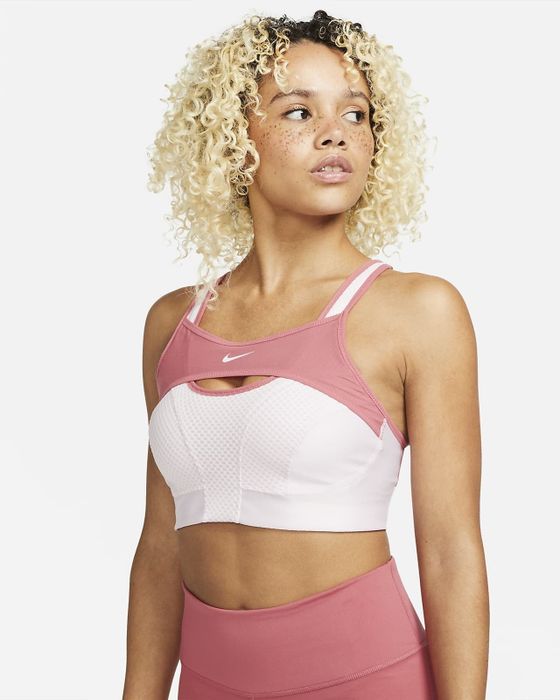 The model is wearing a two-tone pink and white Nike sports bra.