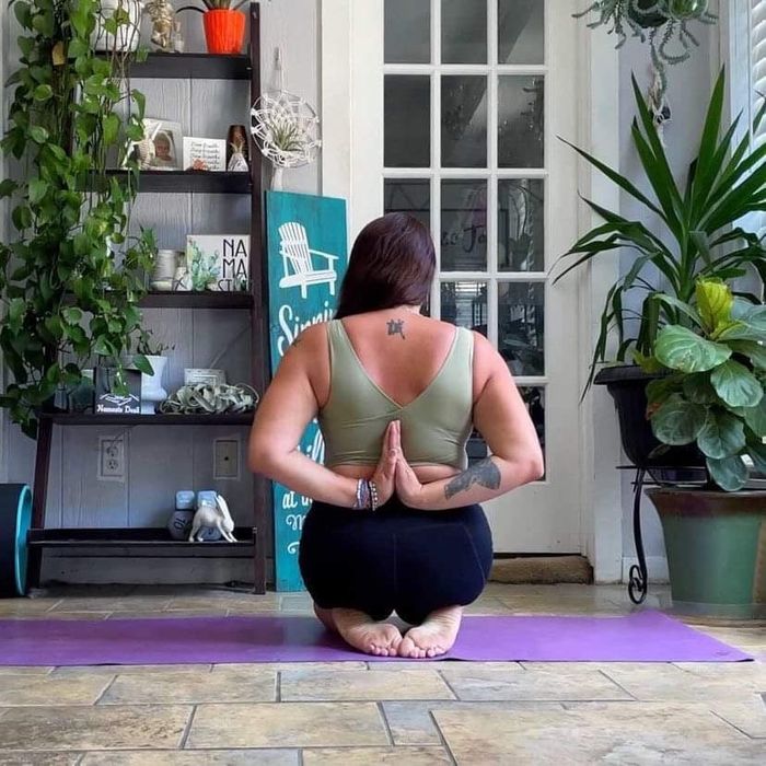 A reviewer wearing a green wire-free sports bra with shorts while holding a yoga pose.