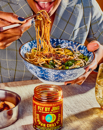 a person enjoying noodles topped with the sauce